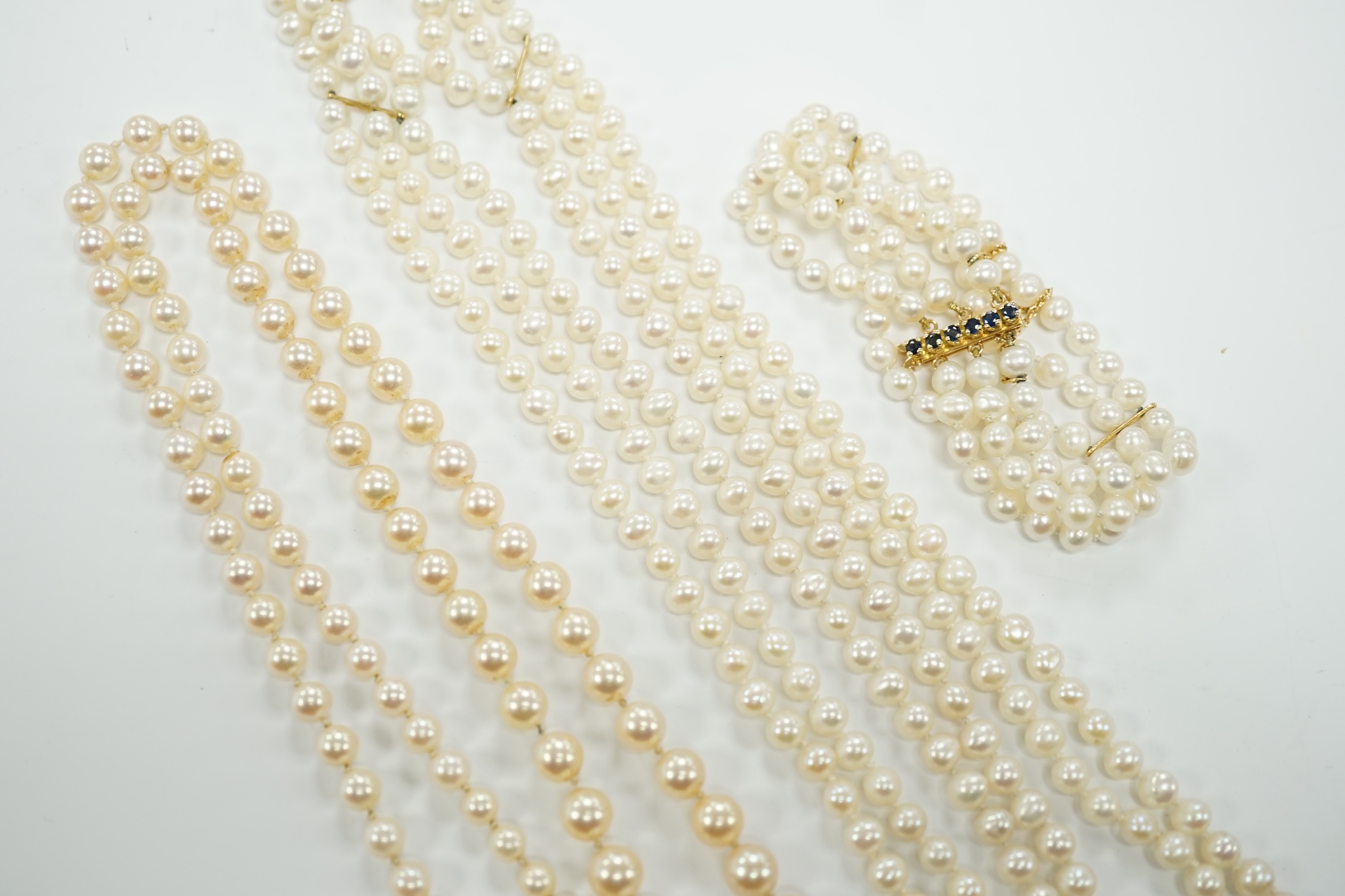 Two Cultured pearl necklaces including a triple strand with yellow metal and sapphire set clasp, 46cm and a matching bracelet.